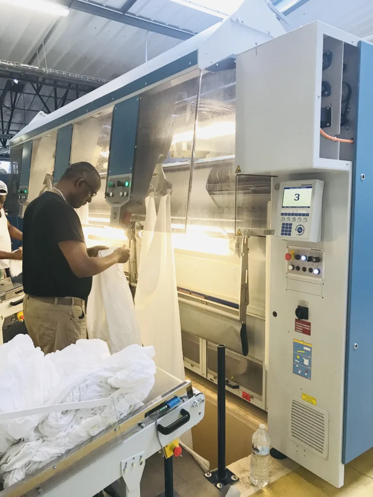Atelier de la blanchisserie Belle Hortense : employé chargeant une machine de finition
