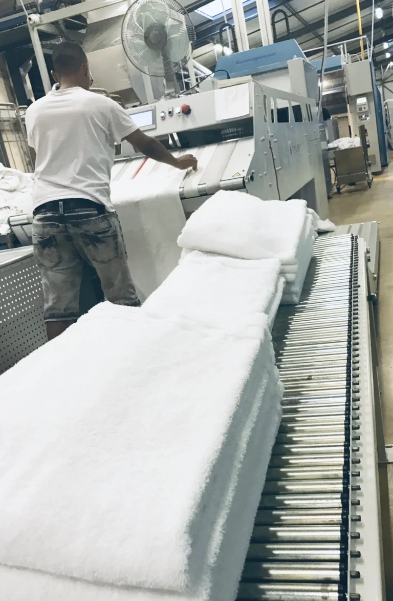 Atelier de la blanchisserie Belle Hortense : employé et piles de serviettes blanches