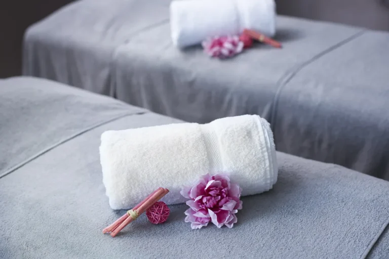 Serviettes blanches roulées sur un lit, avec une fleur