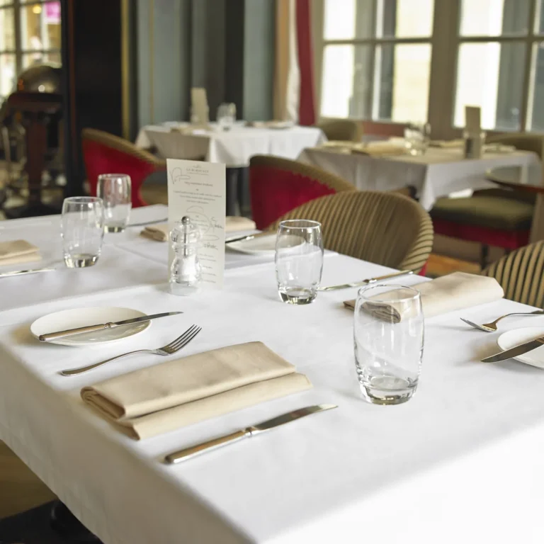 Salle de restaurant dressée, nappes blanches et serviettes beiges