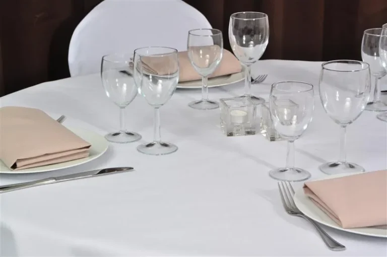 Table dressée, nappe blanche, verres et serviettes roses